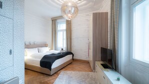 Ein modernes Schlafzimmer mit einem großen Bett, einem Fernseher und einem Fenster mit Vorhängen.