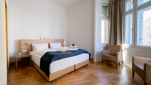A neatly arranged bedroom with a bed, bedside tables, a chair, and a window with curtains. - Vienna Residence, City Hall - Parliament #6410 (Vienna)