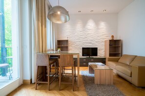 A modern living room with a glass dining table, wooden chairs, a sofa, a TV, and built-in shelving. - Vienna Residence, City Hall - Parliament #6413 (Vienna)