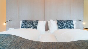A neatly made bed with white linens and two patterned pillows, a wall-mounted light fixture, and a textured headboard. - Vienna Residence, City Hall - Parliament #6415 (Vienna)