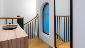 A hallway with a wooden bench, a large mirror, and a window with a blue view. - Vienna Residence, City Hall - Parliament #6415 (Vienna)