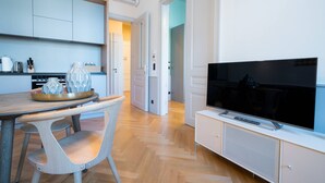 Een moderne keuken met een eetgedeelte, een flatscreen televisie en een gang naar een andere kamer.