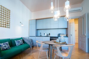 A modern kitchen with white cabinets, a dining table with chairs, and pendant lighting.