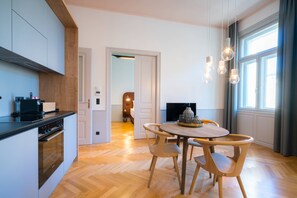 A modern kitchen with a built-in oven and a dining area with a round table and wooden chairs.