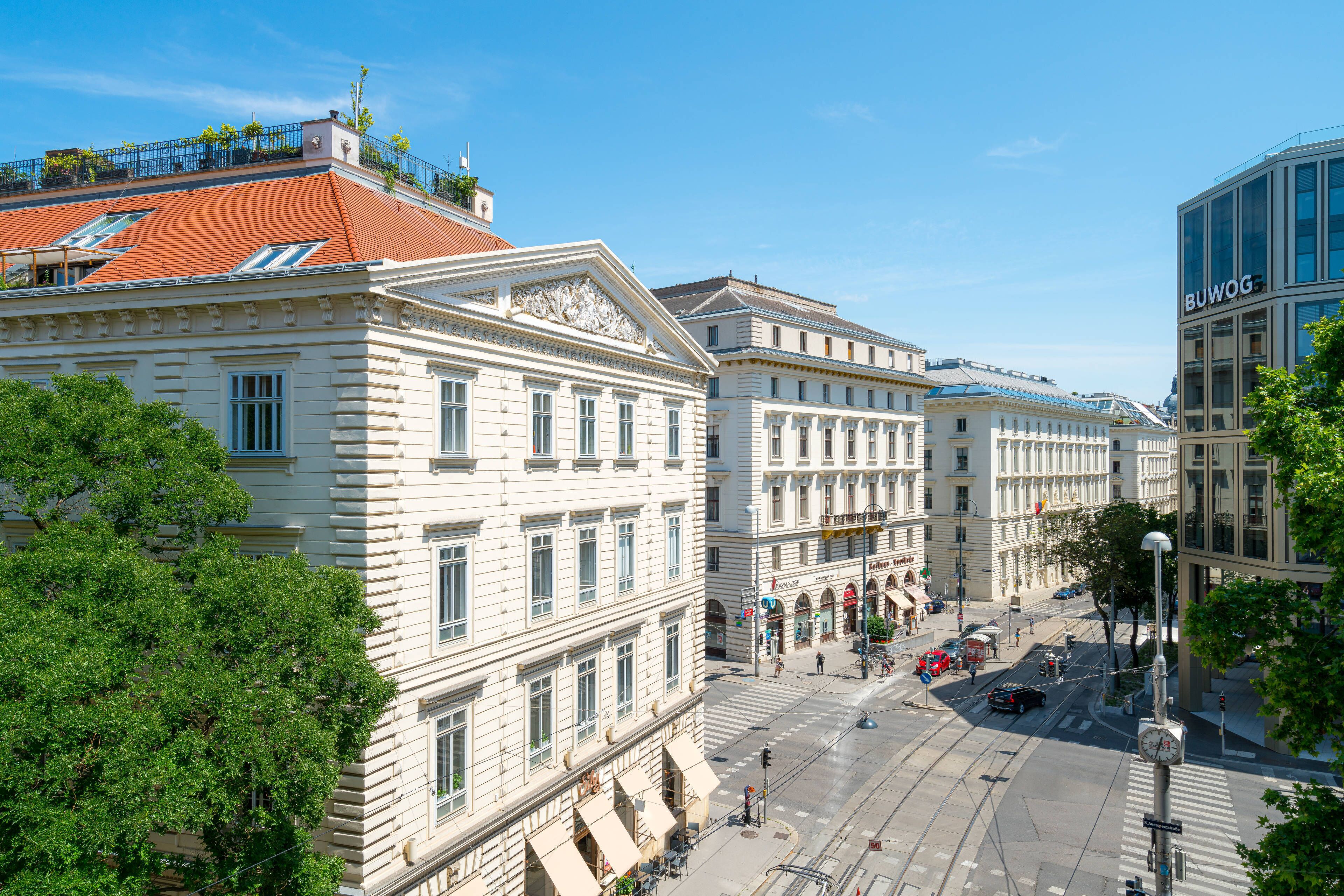 En historisk byggnad med klassisk arkitektur, stora fönster och ett rött tegeltak.