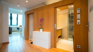Een moderne hotelkamer met houten lambrisering, een witte dressoir, een potplant en een douchecabine van glas.