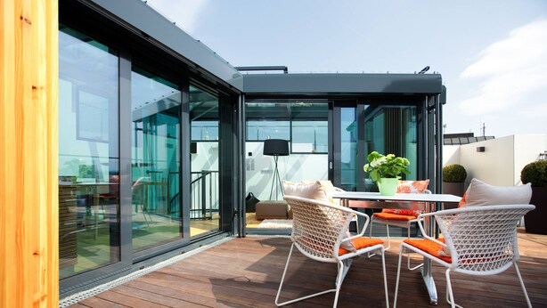 A modern outdoor patio with glass doors, wooden flooring, and white wicker furniture. - Vienna Residence, City Hall - Parliament #6420 (Vienna)