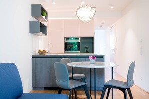 Uma cozinha moderna com armários cinza, uma ilha central e uma mesa redonda com cadeiras.