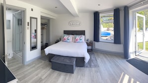 A bedroom with a bed, bedside table, and a view of a swimming pool. - Stunning, Contemporary 1 Bedroom En-suite Annexe (Plymouth)