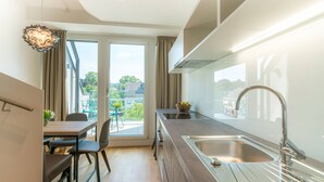 A modern kitchen with a large window, a dining area with a table and chairs, and a view of the outdoors. - Vienna Residence, Hietzing - Schönbrunn #6375 (Vienna)