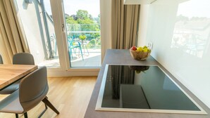 A modern kitchen with a built-in induction cooktop, a wooden dining table with chairs, and a balcony with outdoor furniture. - Vienna Residence, Hietzing - Schönbrunn #6375 (Vienna)
