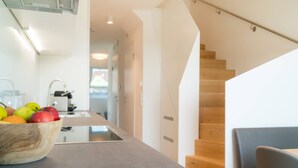 A modern kitchen with a wooden bowl of fruit on the counter, a stainless steel sink, and a staircase leading to another level. - Vienna Residence, Hietzing - Schönbrunn #6375 (Vienna)
