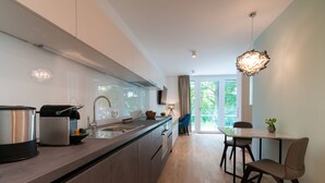 A modern kitchen with a large island, a dining area with a table and chairs, and a view of the outdoors through a glass door. - Vienna Residence, Hietzing - Schönbrunn #6370 (Vienna)