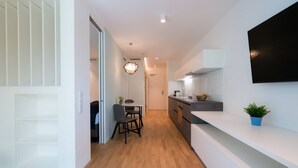 A modern kitchen with a dining area, wooden flooring, and a flat-screen TV mounted on the wall. - Vienna Residence, Hietzing - Schönbrunn #6370 (Vienna)