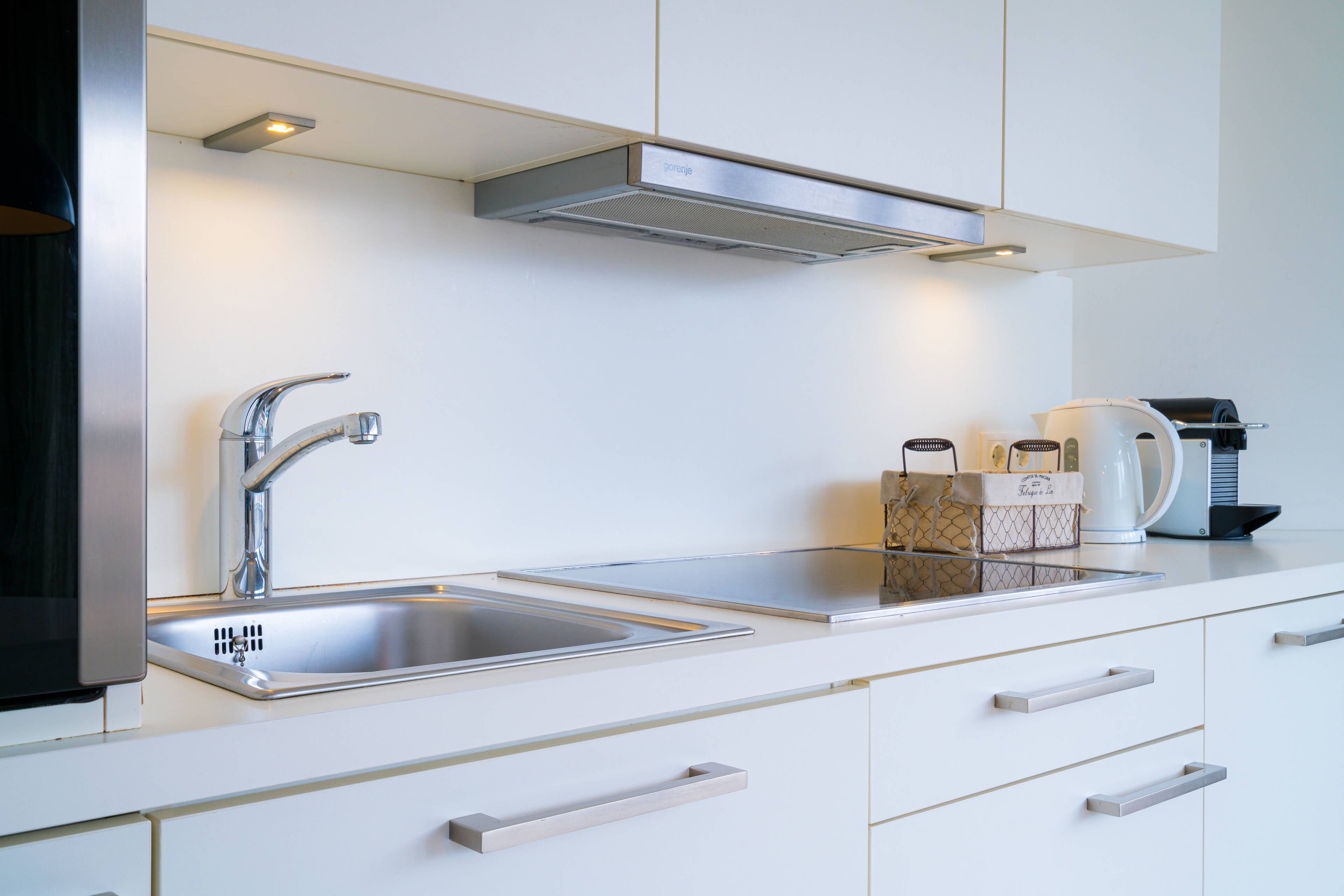 A modern kitchen with stainless steel appliances, a double sink, and white cabinetry.