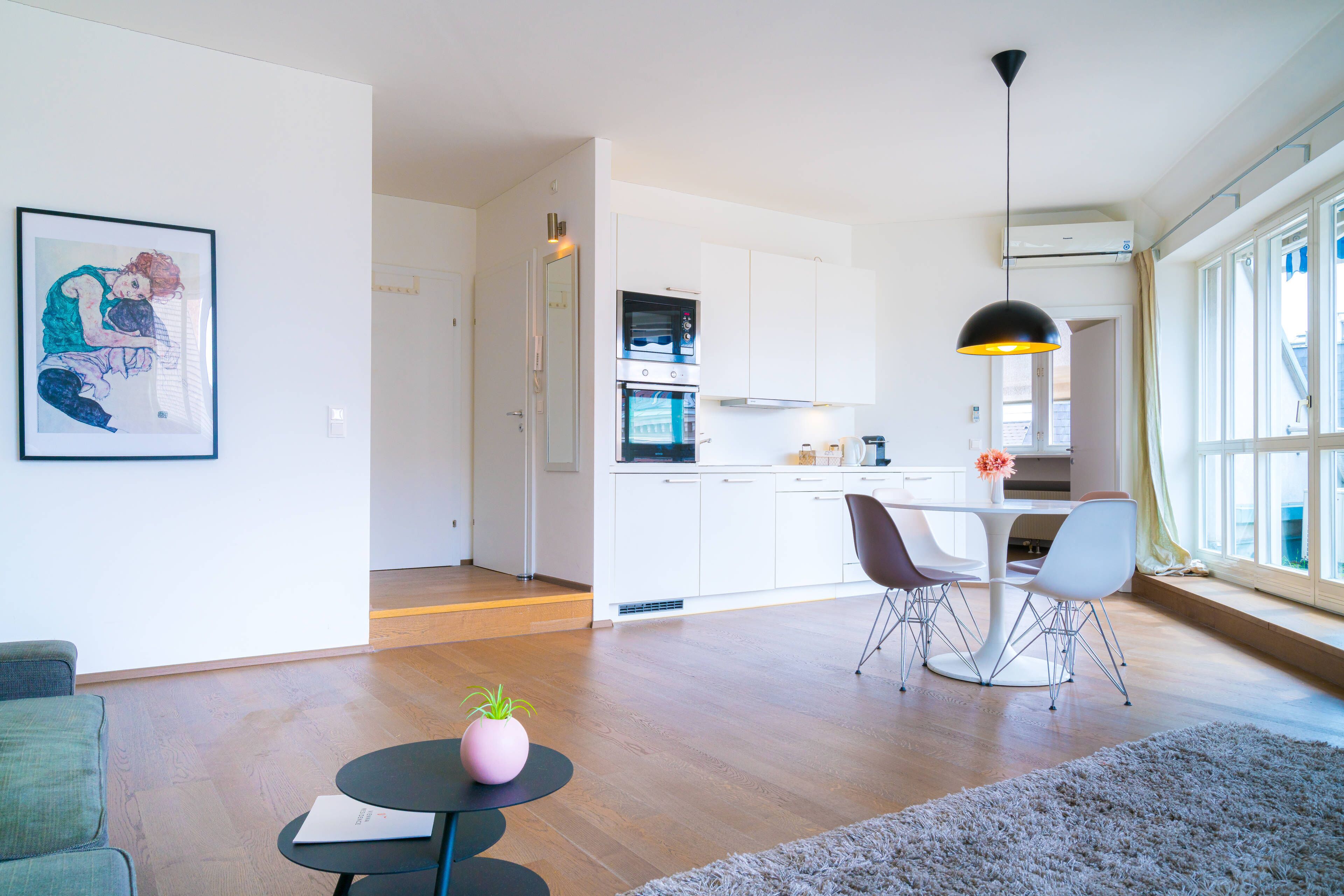 Een moderne woonkamer met een eethoek, keuken en grote ramen.