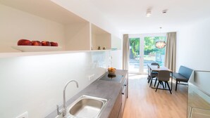 A modern kitchen with a built-in oven, a sink, and a dining area with a table and chairs. - Vienna Residence, Hietzing - Schönbrunn #6362 (Vienna)