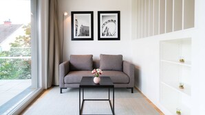 Ein modernes Wohnzimmer mit einem grauen Sofa, einem schwarzen Couchtisch mit einer Vase und zwei gerahmten Bildern an der Wand.