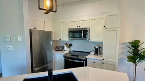 Een moderne keuken met witte kasten, roestvrijstalen apparatuur en een zwart aanrecht.