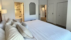 Een slaapkamer met een groot bed, een douche en een gang naar een kast.