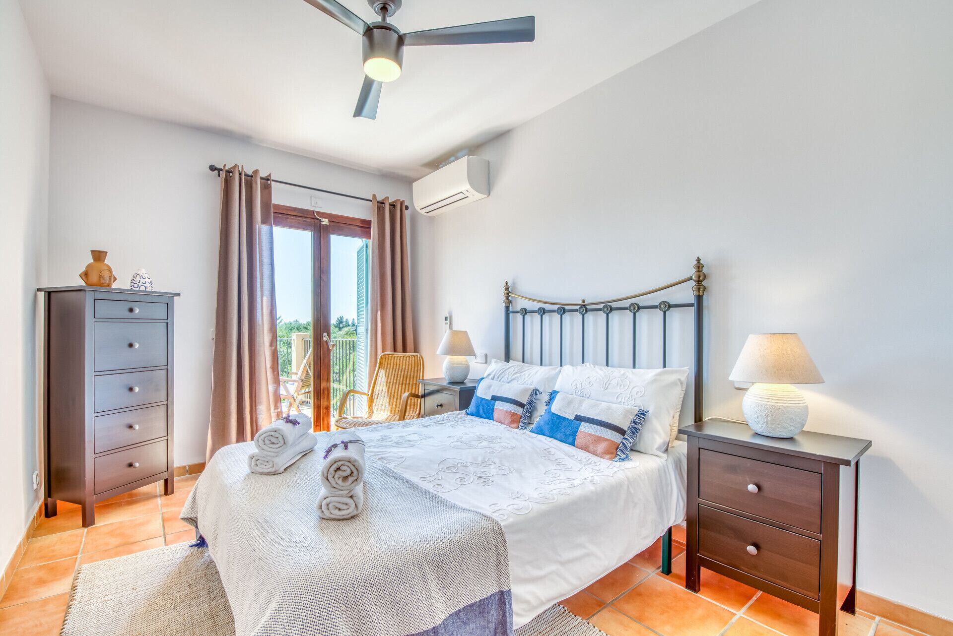 A bedroom with a bed, a nightstand, a dresser, a ceiling fan, and a view through a glass door.