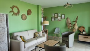 Una sala de estar con una pared verde, un sofá, una mesa de centro, una silla y una lámpara.