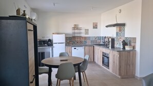 Una cocina moderna con comedor, que incluye una mesa redonda, sillas, un refrigerador, un microondas y una cafetera.