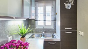 A compact kitchen with a built-in refrigerator, a sink, and a window with blinds. - CASA MYRIAM with view & private parking  (Μαρούσι)