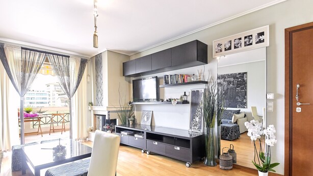 A modern living room with a glass dining table, a sofa, a black entertainment unit, and a cityscape painting. - CASA MYRIAM with view & private parking  (Μαρούσι)