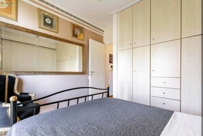 A bedroom with a bed, a large wardrobe, and a mirror on the wall.