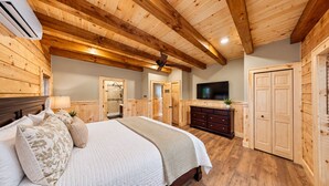 A bedroom with a bed, dresser, TV, and wooden walls. - Grand Peaks Lodge, Luxury Log Home, Views, Hot Tub, Sauna, EV Charger, 3D Tour (Jay)