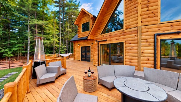 Une cabane en bois dotée d’une terrasse, de meubles d’extérieur et d’une porte vitrée donnant sur l’intérieur.