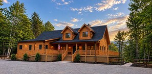 Une cabane en rondins avec une véranda, de nombreuses fenêtres et un drapeau.