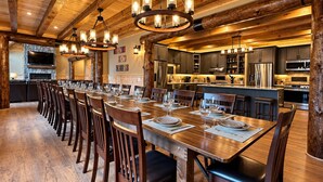 A spacious dining area with a long wooden table, multiple chairs, and a central chandelier. - Grand Peaks Lodge, Luxury Log Home, Views, Hot Tub, Sauna, EV Charger, 3D Tour (Jay)