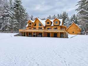 A large wooden lodge with multiple levels and a covered porch, surrounded by snow-covered trees. - Grand Peaks Lodge, Luxury Log Home, Views, Hot Tub, Sauna, EV Charger, 3D Tour (Jay)