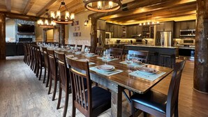 Une vaste salle à manger avec une longue table en bois, dressée pour accueillir de nombreux convives, et entourée de chaises en bois.