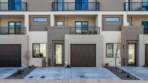 Un immeuble résidentiel moderne à plusieurs étages, doté d’une façade symétrique, de grandes fenêtres et de balcons.