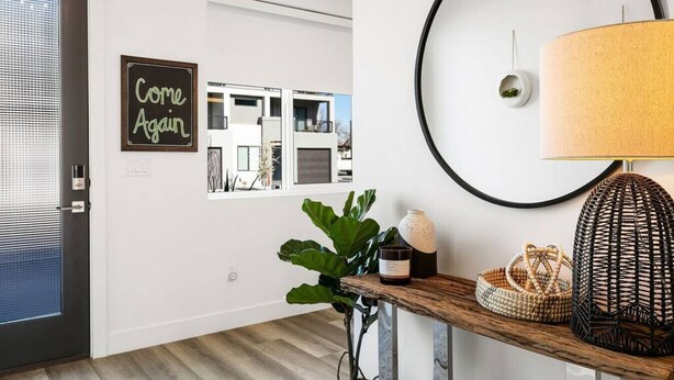 Un intérieur moderne avec un plancher en bois, un applique ronde, un panneau encadré et une plante en pot.