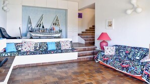 A living room with a sofa, a coffee table, and a staircase leading to an upper floor. - Family villa with sea view classified 3*** - 8 people (Le Lavandou)