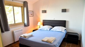 A hotel room with a bed, a nightstand, a lamp, and a window with curtains. - Family villa with sea view classified 3*** - 8 people (Le Lavandou)