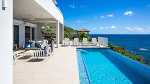 A poolside area with a view of the ocean, outdoor furniture, and a covered seating area. - Aqua (4 bedrooms) - Ocean view villa with pool, Indigo Bay, St. Maarten (Indigo Bay)