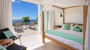A bedroom with a four-poster bed, a balcony with outdoor seating, and a view of the ocean. - Aqua (4 bedrooms) - Ocean view villa with pool, Indigo Bay, St. Maarten (Indigo Bay)