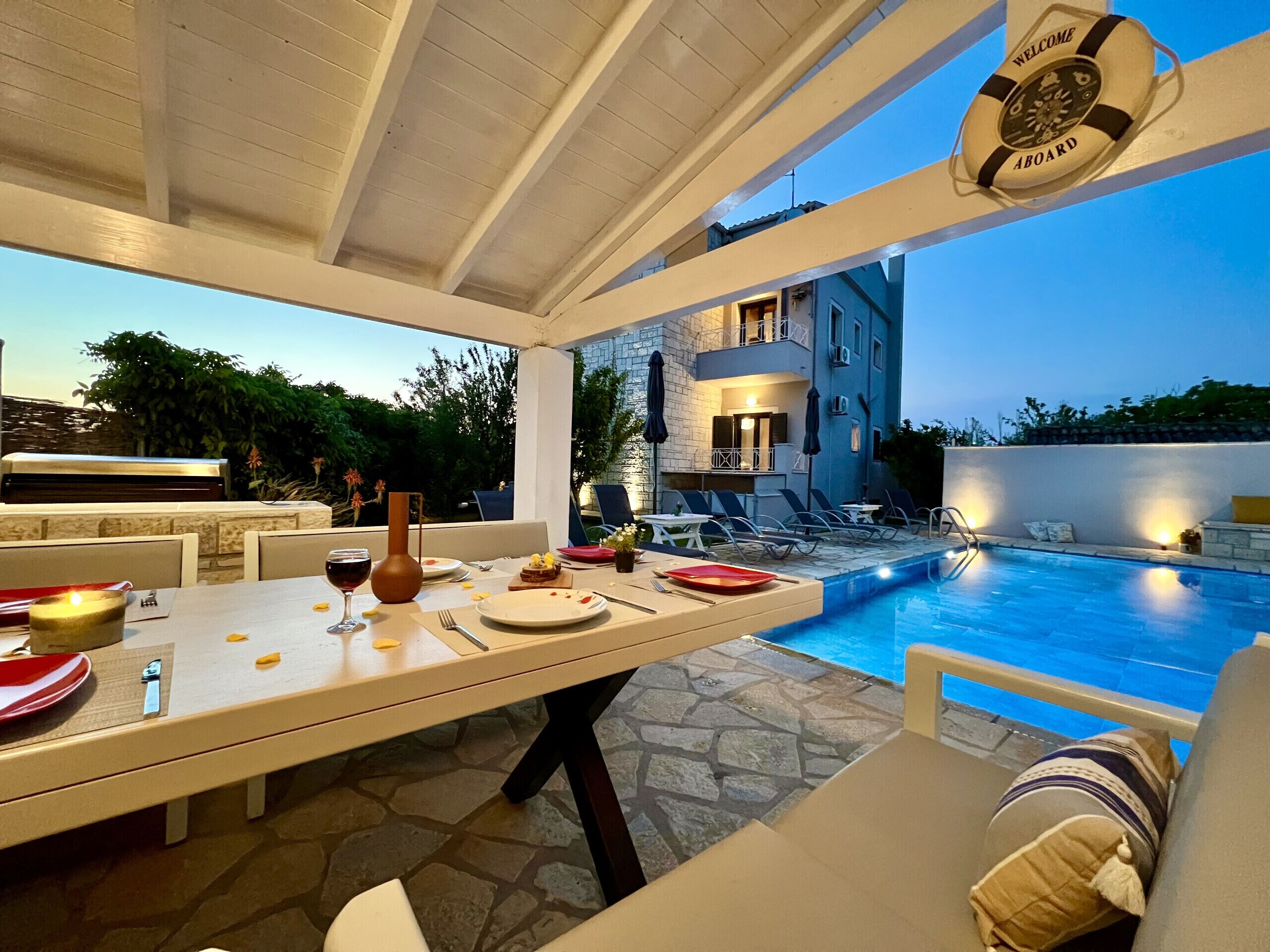 Uma área de refeições com vista para a piscina, um flutuador e um chão de piso de pedra.