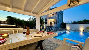 Un espace repas avec vue sur la piscine, une bouée de sauvetage et un sol carrelé en pierre.