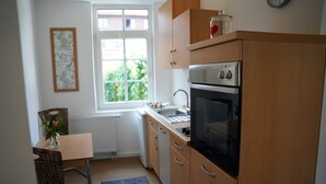 Una cuina petita amb armaris de fusta, un forn de sobre i una finestra que deixa entrar llum natural.