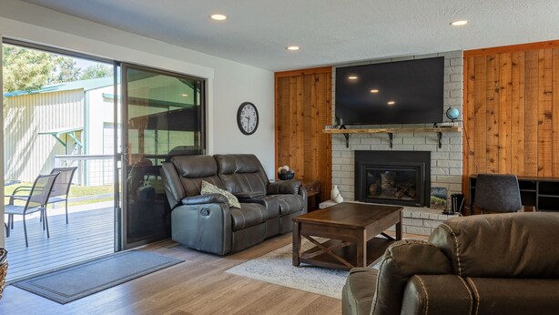 A modern living room with a fireplace, leather sofas, and a large TV. - Spacious 5 Bedroom - Sleeps 14 - Nintendo/Foosball/Games (Coeur d'Alene)