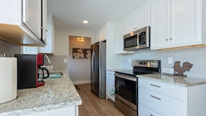 A modern kitchen with white cabinets, stainless steel appliances, and granite countertops. - Spacious 5 Bedroom - Sleeps 14 - Nintendo/Foosball/Games (Coeur d'Alene)