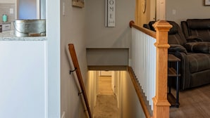 A modern interior with a kitchen area, a wooden staircase, and a seating area with leather recliners. - Spacious 5 Bedroom - Sleeps 14 - Nintendo/Foosball/Games (Coeur d'Alene)