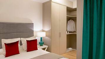 Une chambre d’hôtel avec un lit, une table de chevet avec une lampe, une armoire et un rideau vert.
