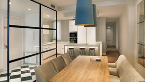 A modern kitchen with a central island, bar stools, and a hanging light fixture.